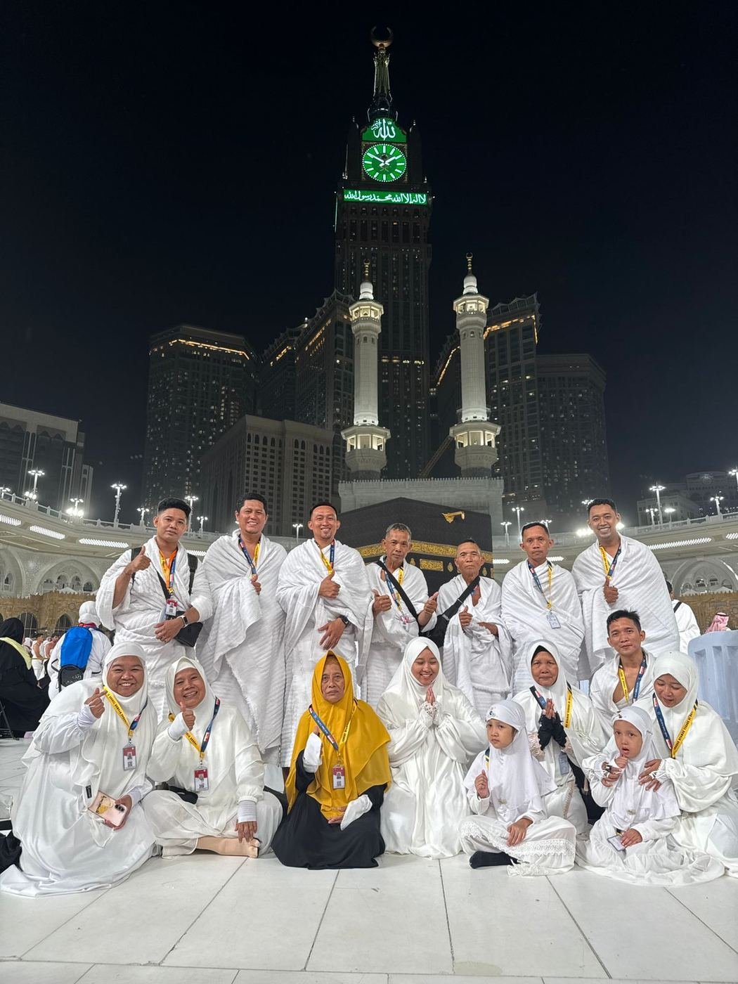 Jamaah Husnul Islam berpakaian ihram di depan Ka'bah dengan latar menara jam Makkah