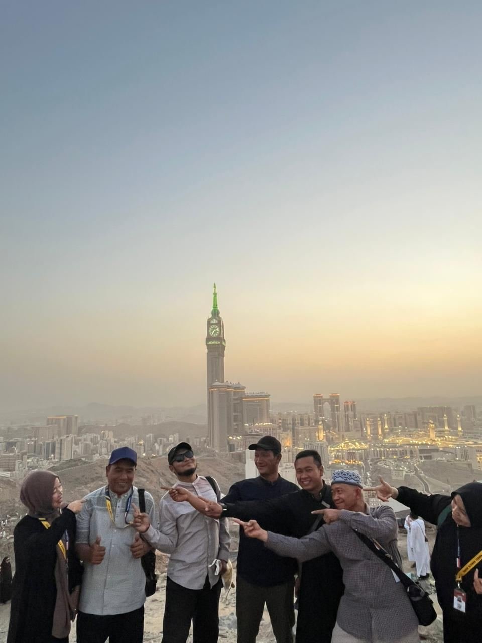 Jamaah Husnul Islam berfoto dengan latar kota Makkah dan menara jam saat senja